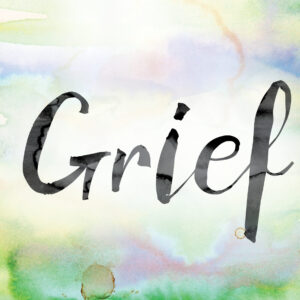 The word "Grief" painted in black ink over a colorful watercolor washed background concept and theme.